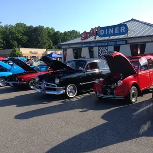 a row of classic cars parked in front of a diner
