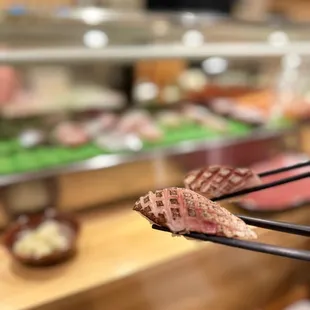 chopsticks holding a piece of meat