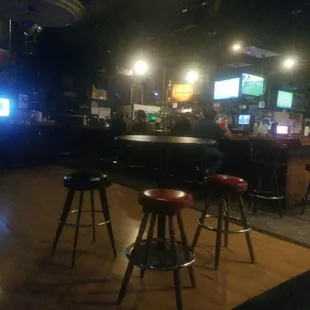a bar with stools and televisions
