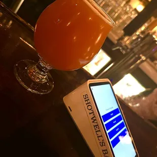 a glass of beer next to a cell phone