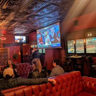 people sitting on red couches watching tv