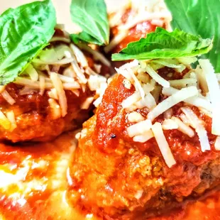 two meatballs covered in sauce and cheese