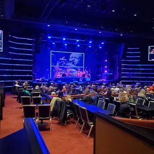 people sitting at tables in front of a stage