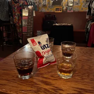 two glasses of whiskey and a bag of chips