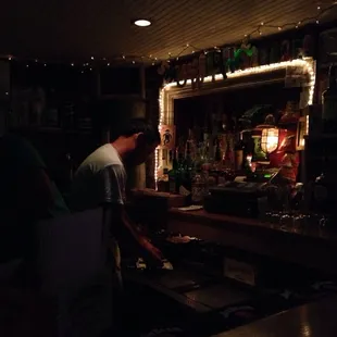 a man preparing a drink in a dimly lit bar