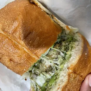 Chicken pesto sandwich with mozzarella, mushrooms, green bell peppers, and onions