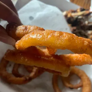 a hand holding a piece of onion rings
