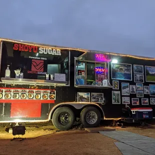 Food truck located in the back. There is parking right in front of the truck and a small eating area