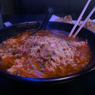 a bowl of soup with chopsticks