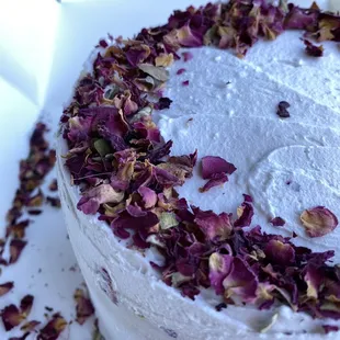 a frosted cake with rose petals on top