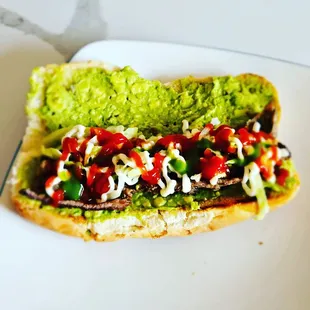a hot dog with guacamole and tomatoes