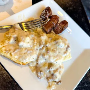 Sausage biscuit and gravy with a sausage link.