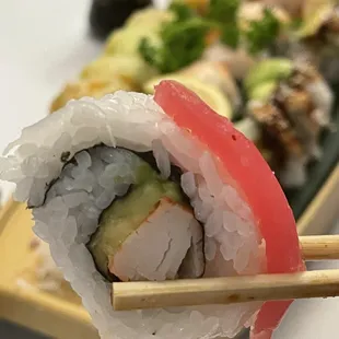 a close up of a sushi roll with chopsticks