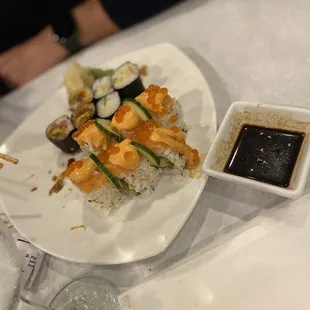 a plate of sushi and sauce on a table