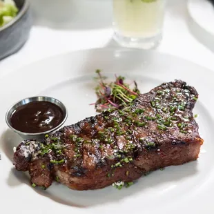 a steak on a plate with a side of salad