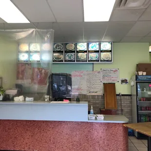 a restaurant counter with menus on the wall