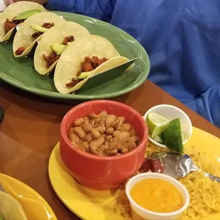 Tacos al Pastor. Tacos are topped with cilantro and onion and comes with rice and beans