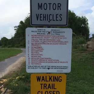 a no motor vehicles sign and a walking trail closed sign
