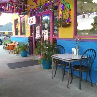 the outside of a restaurant with tables and chairs