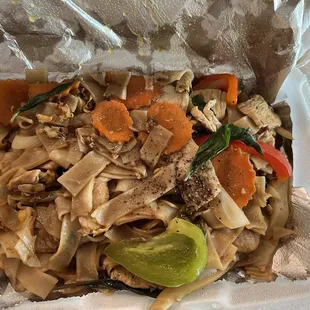 a take out container of noodles and vegetables