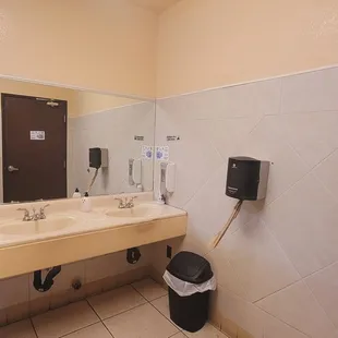 a bathroom with two sinks and a trash can