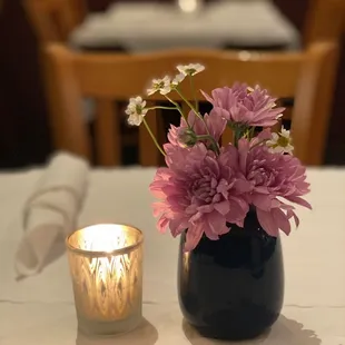 a vase of flowers and a candle on a table