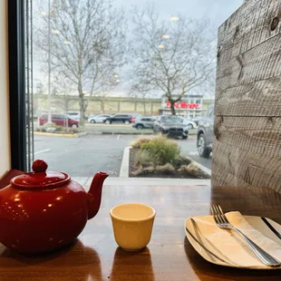 a red teapot and a cup on a table