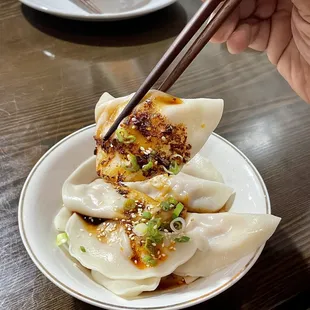 a plate of dumplings with chopsticks
