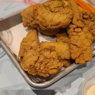 a tray of fried chicken and dipping sauces