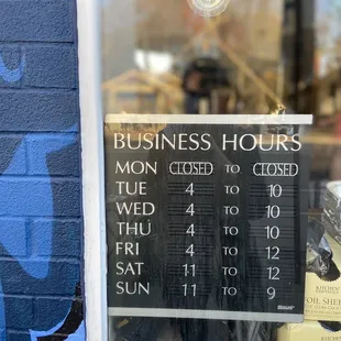 a business hours sign in a window