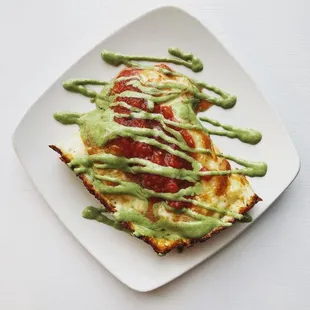 green sauce drizzled over a slice of pizza