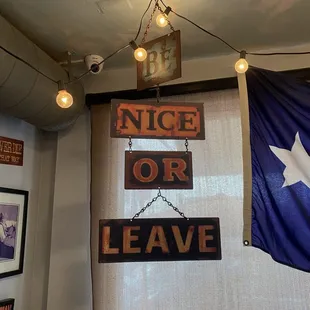 a nice or leave sign hanging from the ceiling