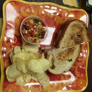Rachel Sandwich (corned beef, Swiss cheese, coleslaw, Russian  dressing, on toasted rye) with relish dish, and chips. Cup of Seafood Gumbo.