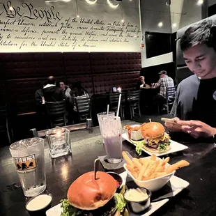 a man sitting at a table with a hamburger and fries