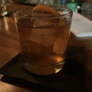 a glass of whiskey with ice on a coaster