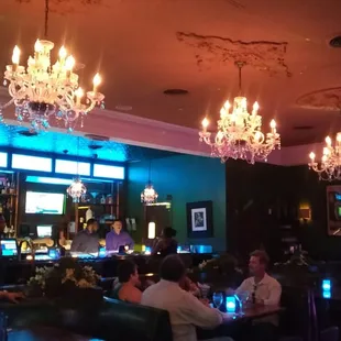 people sitting at a bar with chandeliers