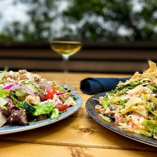 two plates of salad and a glass of wine