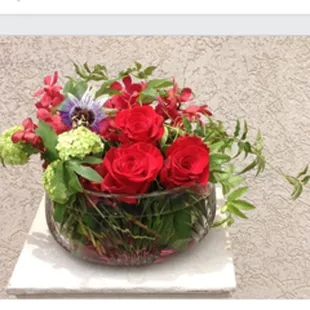 Glass bowl filled with curly willow and seasonal summer flowers