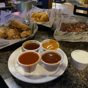 Naked wings, waffle fries, rib appetizer, and various sauces