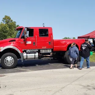 a group of people standing around a large red truck