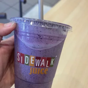 a hand holding a purple drink
