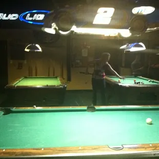 two people playing pool in a dimly lit room