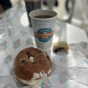 a half eaten bagel and a cup of coffee