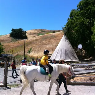 My son riding a white horse.