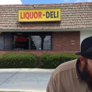 a man sitting outside of a liquor deli