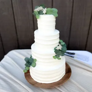 Four tier wedding cake with greenery