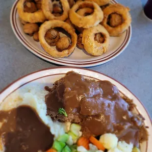 Meatloaf dinner with a combination side of onion rings and fried mushrooms.