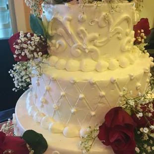 a white wedding cake with red roses