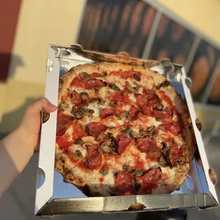 a person holding a pizza in a box