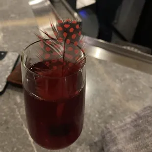 a glass of wine with a feather on top